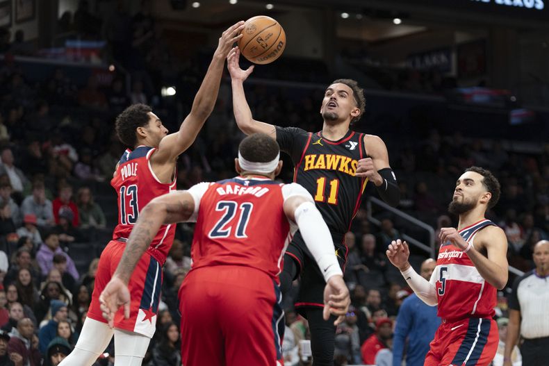 Trae Young (11) de los Hawks de Atlanta disputa el balón ante Jordan Poole (13) de los Wizards de Washington durante la segunda mitad del juego de baloncesto de la NBA el domingo 31 de diciembre, en Washington. (AP Foto/Jose Luis Magana)