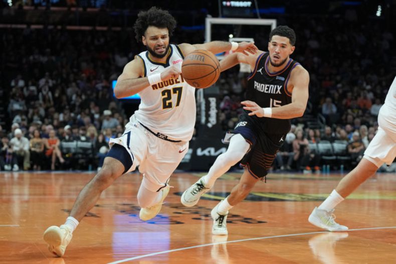 Jamal Murray (27), de los Nuggets de Denver, lleva el balón escapando de Devin Booker, de los Suns de Phoenix, durante la segunda mitad del juego de balocesto de la Copa NBA, el viernes 30 de octubre de 2026, en Phoenix. (AP Foto/Rick Scuteri)