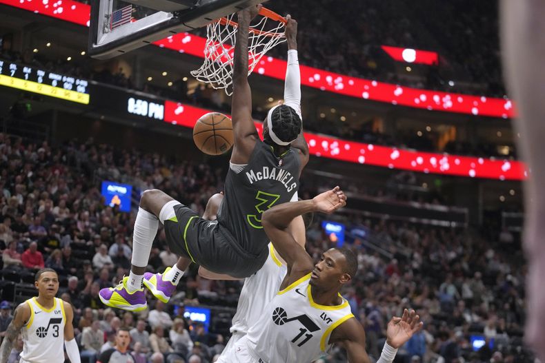 El alero de los Timberwolves de Minnesota, Jaden McDaniels (3), clava contra el escolta del Jazz de Utah, Kris Dunn (11), durante la segunda mitad del partido de baloncesto de la NBA, el sábado 16 de marzo de 2024, en Salt Lake City. (AP Foto/Rick Bowmer)