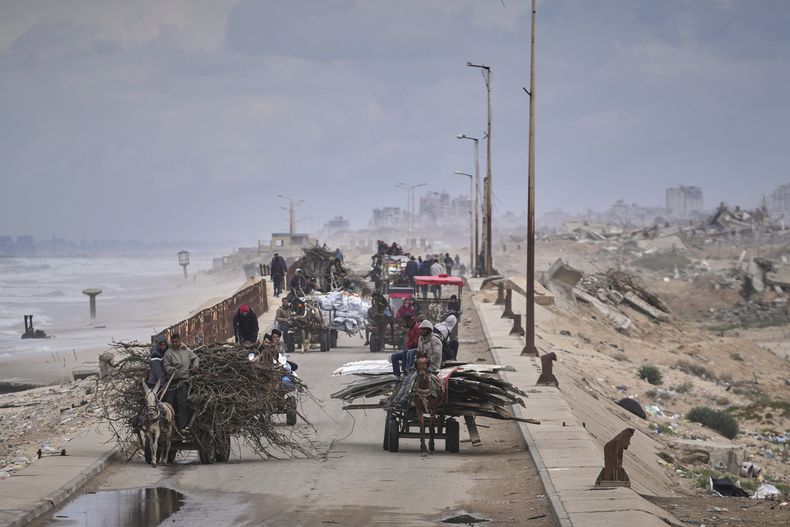 Palestinos desplazados, cargados con sus pertenencias, madera y otros artículos, van del sur al norte de Gaza por la carretera costera, lejos de las zonas donde opera el ejército israelí tras la reanudación de su ofensiva sobre la Franja, a las afueras de la Ciudad de Gaza, el 21 de marzo de 2025. (AP Foto/Abdel Kareem Hana)