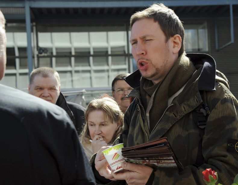 ARCHIVO - Paavo Arhinmaki, a la derecha, entonces líder del partido Vasemmistoliitto (Alianza de Izquierda) y candidato al parlamento finlandés, se reúne con votantes durante la campaña electoral del partido en Helsinki, Finlandia, el sábado 16 de abril de 2011. El actual teniente de alcalde de la capital de Finlandia, Arhinmaki, enfrenta posibles acciones legales, llamados para que renuncie y el pago de una indemnización por daños y perjuicios después de que lo sorprendieran con las manos en la masa pintando un graffiti con aerosol en un túnel ferroviario el viernes 23 de junio de 2023. (Sari Gustafsson/Lehtikuva vía AP, archivo)