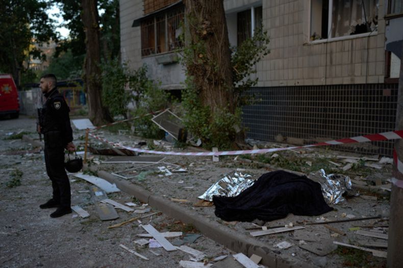 Un policía, junto a los cadáveres de dos personas muertas durante un ataque nocturno ruso en Kiev, Ucrania, el 20 de agosto de 2026. (AP Foto/Francisco Seco)