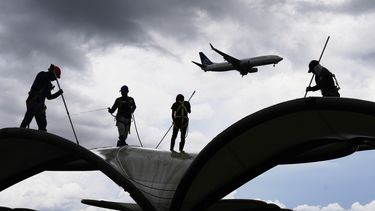 Los trabajadores limpian un techo en el Aeropuerto Internacional de Tocumen en la Ciudad de Panamá, el jueves 22 de mayo de 2025, mientras Panamá y Venezuela se preparan para reanudar los vuelos comerciales. (AP Foto/Matías Delacroix)