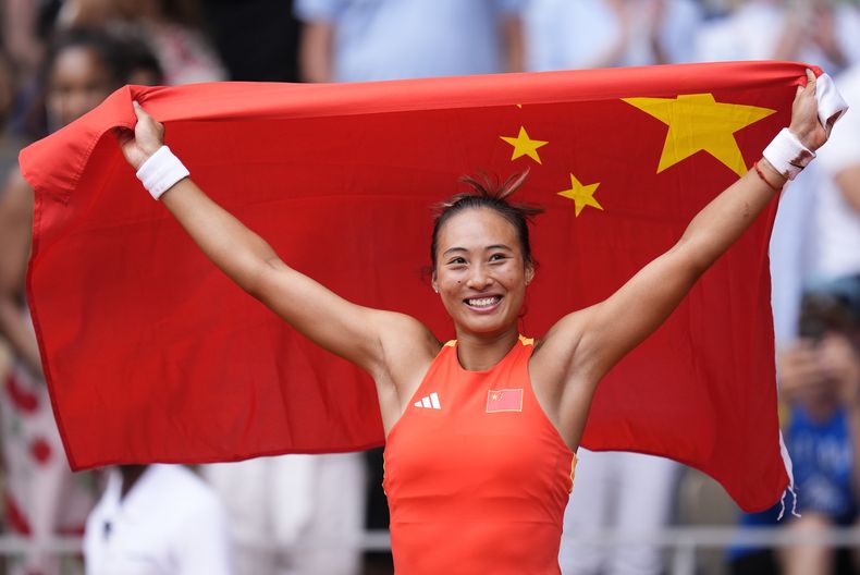 La china Zheng Qinwen posa con la bandera de su país al vencer a la croata Donna Vekic en la final del torneo de tenis de los Juegos Olímpicos el sábado 3 de agosto del 2024. (AP Foto/Manu Fernandez)