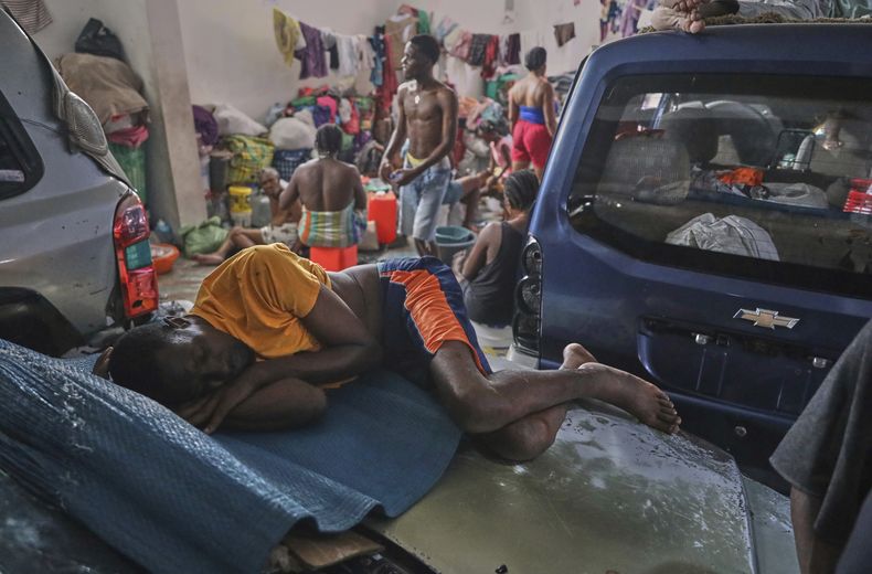 Un hombre duerme en un automóvil en un albergue para familias desplazadas por la violencia de pandillas en Puerto Príncipe, Haití, el lunes 12 de mayo de 2025. (AP Foto/Odelyn Joseph)