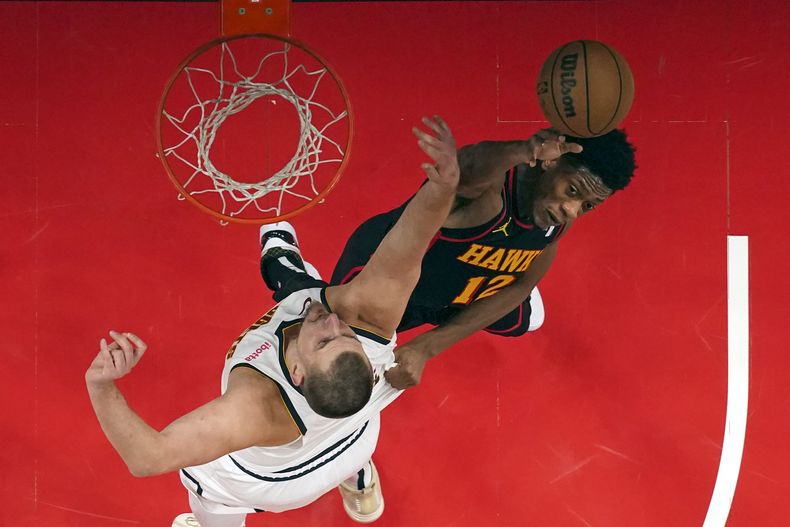 Nikola Jokic (15), pívot de los Nuggets de Denver, y el alero DeAndre Hunter (12), de los Hawks de Atlanta, disputan un rebote en la primera mitad del juego de baloncesto de la NBA, el domingo 8 de diciembre de 2024, en Atlanta. (AP Foto/John Bazemore)