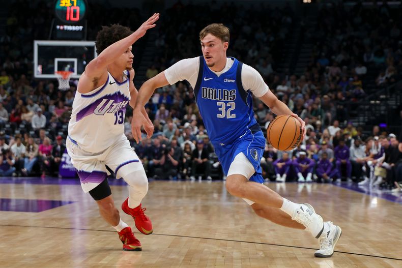 Cooper Flagg (32), alero novato de los Mavericks de Dallas, conduce el balón frente a Walter Clayton Jr. (13), del Jazz de Utah, durante la primera mitad del juego de pretemporada del baloncesto de la NBA, el lunes 13 de octubre de 2025, en Salt Lake City. (AP Foto/Rob Gray)