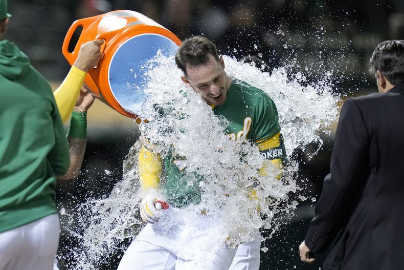 Brent Rooker, de los Atléticos de Oakland, recibe una ducha de agua helada tras sacudir un jonrón de tres carreras que dio la victoria a su equipo frente a los Rangers de Texas en el 10mo inning del juego de la MLB que los enfrentó en Oakland, California, el 12 de mayo de 2023. (AP Foto/Godofredo A. Vásquez)