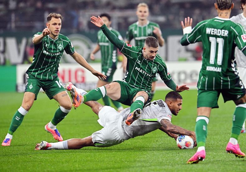 Romano Schmid, de el Bremen, arriba, lucha por el balón contra Vinicius Souza, de el Wolfsburg, durante el juego de fútbol de la Bundesliga alemana entre el Werder Bremen y el VfL Wolfsburg en Bremen, Alemania, el viernes 7 de noviembre de 2025. (Carmen Jaspersen/dpa vía AP)
