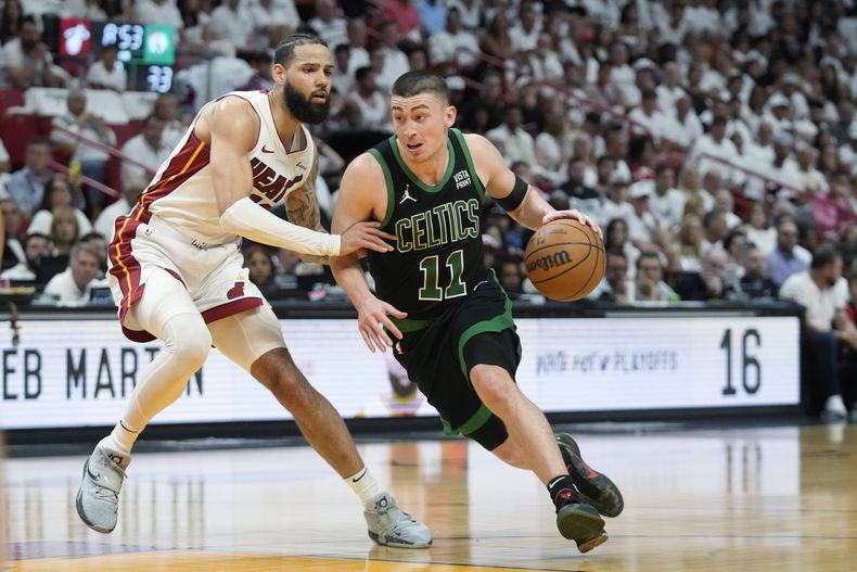 El base de los Celtics de Boston Payton Pritchard avanza con el balón hacia la canasta frente al alero del Heat de Miami Caleb Martin en el juego 3 de la primera ronda de la postemporada el sábado 27 de abril del 2024. (AP Foto/Wilfredo Lee)