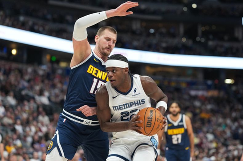 Taylor Hendricks (frente), delantero de los Grizzlies de Memphis, se dirige hacia el aro mientras el defensa Nikola Jokić, centro de los Nuggets de Denver, marca su camino durante la primera mitad de un juego de baloncesto de la NBA, el miércoles 8 de abril de 2026, en Denver. (Foto AP/David Zalubowski)