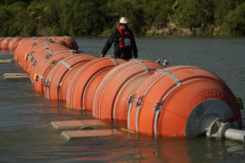 ARCHIVO - Un kayaquista camina junto a las grandes boyas usadas como barrera fronteriza flotante en el río Grande, o Bravo, el 1 de agosto de 2023, en Eagle Pass, Texas. (AP Foto/Eric Gay, Archivo)