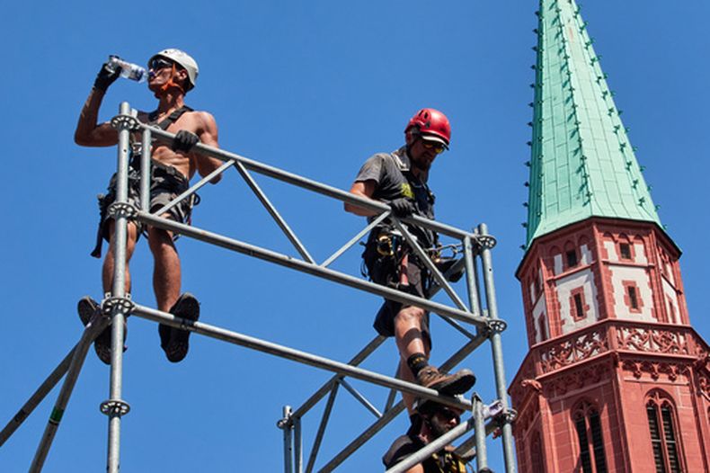 Un operario toma agua mientras instala un escenario para un triatlón Ironman, en Fráncfort, Alemania, el 25 de junio de 2026. (AP Foto/Michael Probst)