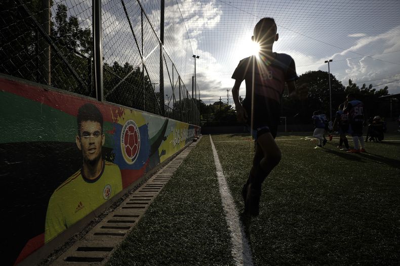 Jóvenes futbolistas entrenan en el Club Bayer de fútbol escolar, fundado por Luis Manuel Díaz, padre del jugador de la selección de Colombia y del equipo inglés Liverpool Luis Díaz, representado en una pintura en la pared a la izquierda, en Barrancas, Colombia, el miércoles 8 de noviembre de 2023. Luis Manuel Díaz fue secuestrado el 28 de octubre por la guerrilla Ejército de Liberación Nacional. (AP Foto/Iván Valencia)