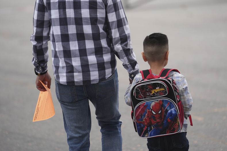 Un padre y su hijo llegan al primer día de clases, el jueves 14 de agosto de 2025, en Los Ángeles. (AP Foto/Marcio José Sánchez)