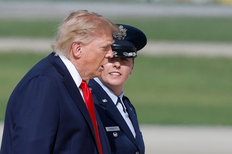 El presidente Donald Trump es escoltado por la subcomandante de la 89º Ala Aérea de la Fuerza Aérea, Melissa Dombrock, derecha, mientras camina desde el Marine One antes de abordar el Air Force One, el viernes 21 de agosto de 2026, en la Base Conjunta Andrews, en Maryland. (AP Foto/Luis M. Alvarez)
