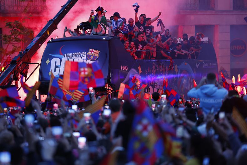Jugadores del equipo femenino y masculino del Barcelona celebran en un autobús destapado la obtención de los títulos de liga por las calles de la capital catalana el lunes 15 de mayo del 2023.(AP Foto/Joan Monfort)