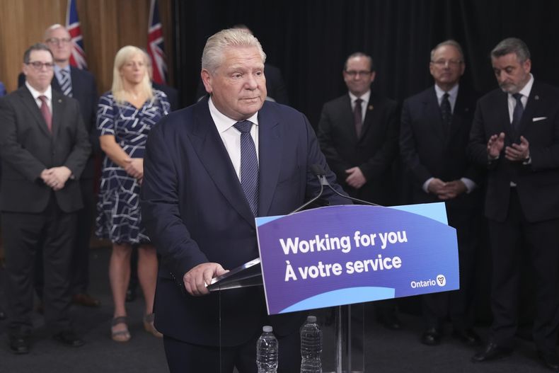 El primer ministro de Ontario, Doug Ford, habla con los medios de comunicación mientras algunos alcaldes y ministros del gobierno observan en Queens Park en Toronto el jueves 12 de diciembre de 2024. (Chris Young/The Canadian Press vía AP)