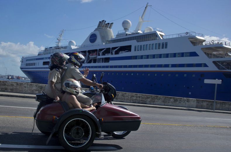 En esta fotograf&iacute;a del 9 de diciembre de 2013, un tr&iacute;o de personas a bordo de una motocicleta pasan al lado del crucero "Semester at Sea" atracado en la bah&iacute;a de La Habana, Cuba. El anuncio el mi&eacute;rcoles por el preside