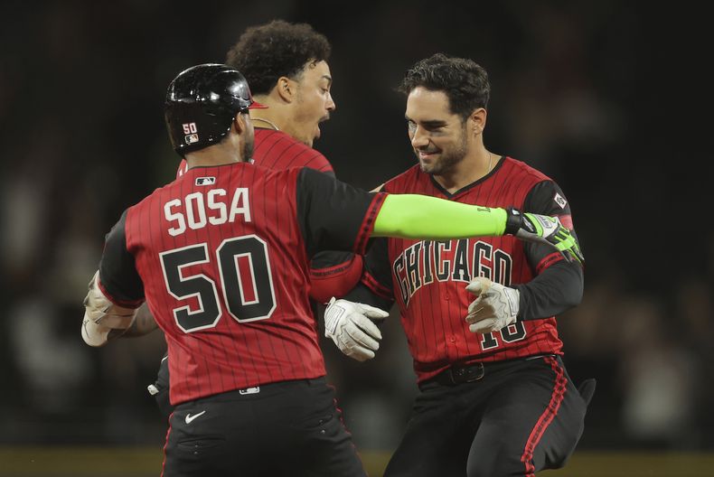 Mike Tauchman (derecha), festeja con sus compañeros de los Medias Blancas de Chicago, el cubano Miguel Vargas y el venezolano Lenyn Sosa, tras pegar el hit decisivo en el duelo ante los Guardianes de Cleveland, el viernes 11 de julio de 2025 (AP Foto/Melissa Tamez)