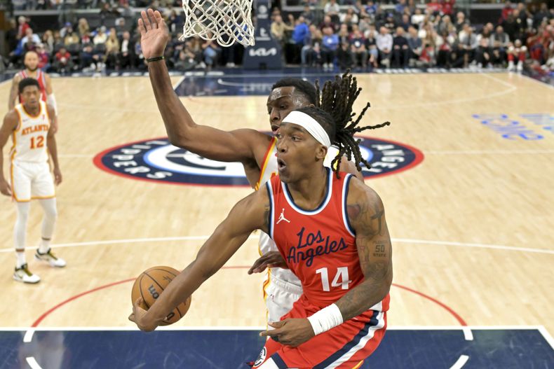 El escolta de los Clippers de Los Ángeles, Terance Mann (14), hace un pase alrededor del alero de los Hawks de Atlanta, Onyeka Okongwu, durante la segunda mitad de un partido de baloncesto de la NBA, el sábado 4 de enero de 2025, en Los Ángeles. (AP Foto/Jayne-Kamin-Oncea)