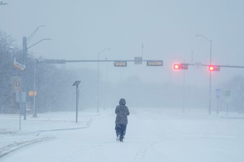 Una persona corre en una avenida cubierta de nueve durante una tormenta invernal, el lunes 15 de enero de 2024, en Grand Prairie, Texas. (AP Foto/Julio Cortez)