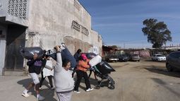 La venezolana Margelis Rodríguez, en el centro, empuja un carrito lleno de ropa mientras su familia y otras personas de un refugio de migrantes caminan a una lavandería cercana en Tijuana, México, el viernes 31 de enero de 2025. (AP Foto/Gregory Bull)