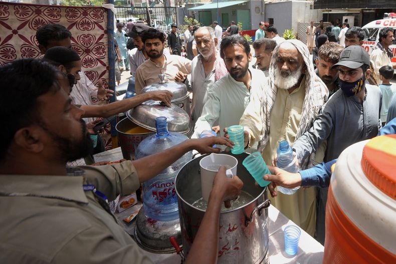 Voluntarios ofrecen agua con limón y azúcar a la gente en un campamento habilitado para evitar golpes de calor en un caluroso día de verano en Karachi, Pakistán, el jueves 23 de mayo de 2024. Los médicos atendían a cientos de victimas de golpes de calor en varios hospitales del país tras el inicio de un intenso episodio de altas temperaturas. (AP Foto/Fareed Khan)