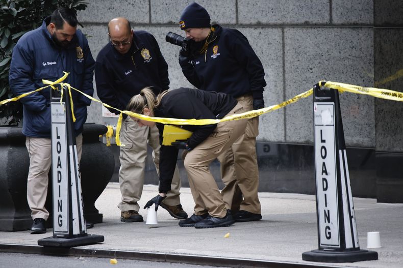 Agentes de la unidad de asesinatos de la policía de Nueva York colocan vasos para marcar los lugares donde cayeron las balas mientras investigan en las inmediaciones del hotel Hilton de Manhattan, donde Brian Thompson, CEO of UnitedHealthcare, fue asesinato a tiros, el 4 de diciembre de 2024, en Nueva York. (AP Foto/Stefan Jeremiah)