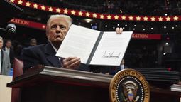 El presidente Donald Trump firma una orden ejecutiva durante un desfile bajo techo por la inauguración presidencial en el estadio Capital One, el lunes 20 de enero de 2025, en Washington. (AP Foto/Evan Vucci)