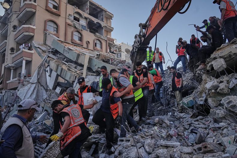 Equipos de defensa civil palestinos cargan con un cuerpo rescatado de entre los escombros de un edificio derrumbado en el que vivían familias palestinas desplazadas y que había sufrido daños importantes durante la guerra entre Israel y Hamás, en la Ciudad de Gaza, el 16 de septiembre de 2026. (AP Foto/Jehad Alshrafi)