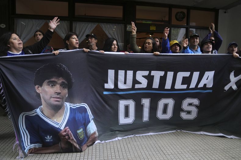 Seguidores del fallecido Diego Maradona sostienen una pancarta con la frase Justicia para Dios afuera del tribunal donde se realiza el juicio de homicidio por negligencia contra el personal médico que trató a Maradona, el martes 11 de marzo de 2025, en las afueras de Buenos Aires. (AP Foto/Natacha Pisarenko)