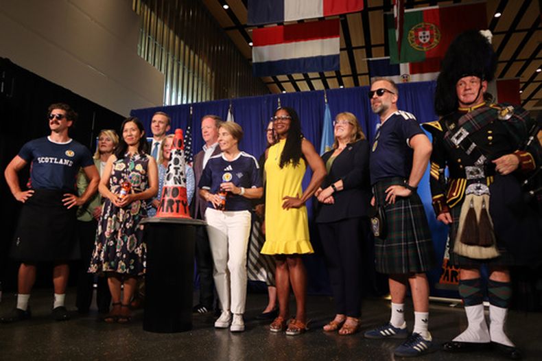 Laalcaldesa de Boston Michelle Wu (centro-izquierda) y la gobernadora de Massachusetts Maura Healey (centro-derecha) posan con hinchas escoceses durante una ceremonia en el Aeropuerto Internacional Logan, el martes 14 de julio de 2026 (AP Foto/Leah Willingham)