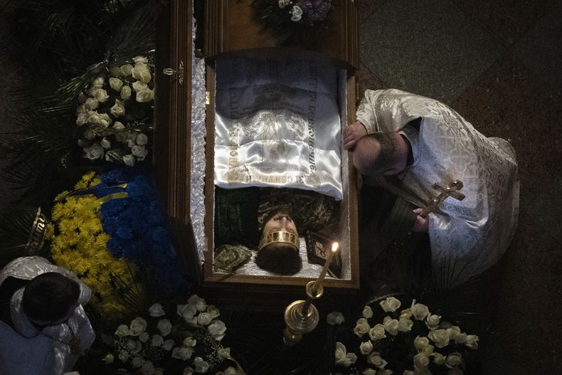 Un sacerdote al lado del féretro del poeta y soldado ucraniano Maksym Kryvtsov, en Kiev, el 11 de enero de 2024. (Foto AP /Efrem Lukatsky)