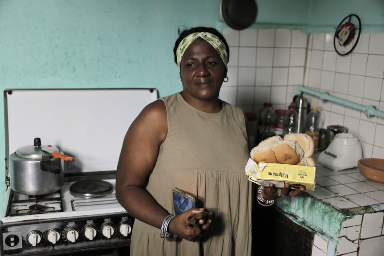 María de los Ángeles Pozo, trabajadora retirada de una escuela, posa para una foto en su cocina con algunos de los alimentos subvencionados que recibió por con la libreta de abastecimiento estatal en La Habana, Cuba, el miércoles 6 de marzo de 2024. Pozo recordó con una sonrisa cuando con su libreta de abastecimiento conseguía de todo: desde pasteles de boda, hamburguesas, pescado y chocolate a leche condensada, fósforos, cerveza, harina y hasta cepillos de dientes. (AP Foto /Ariel Ley)