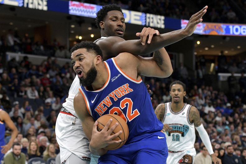 El pívot de los Knicks de Nueva York, Karl-Anthony Towns, al frente, maneja el balón contra el alero de los Grizzlies de Memphis, Jaren Jackson Jr., arriba, en la segunda mitad de un partido de baloncesto de la NBA, el viernes 28 de febrero de 2025, en Memphis, Tennessee. (AP Foto/Brandon Dill)
