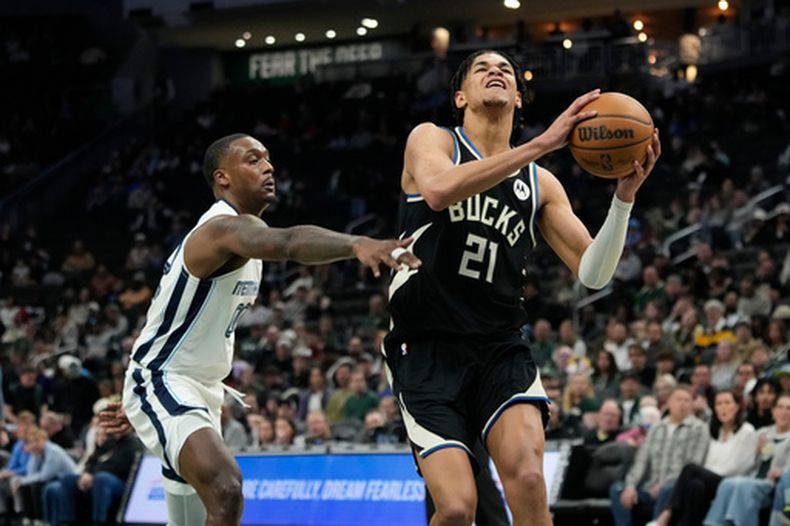 Ousmane Dieng (21), de el Bucks de Milwaukee, se dirige hacia la canasta ante la defensa Dariq Whitehead, de los Grizzlies de Memphis, durante la primera mitad de un juego de baloncesto de la NBA, el domingo 5 de abril de 2026, en Milwaukee. (Foto AP/Aaron Gash)