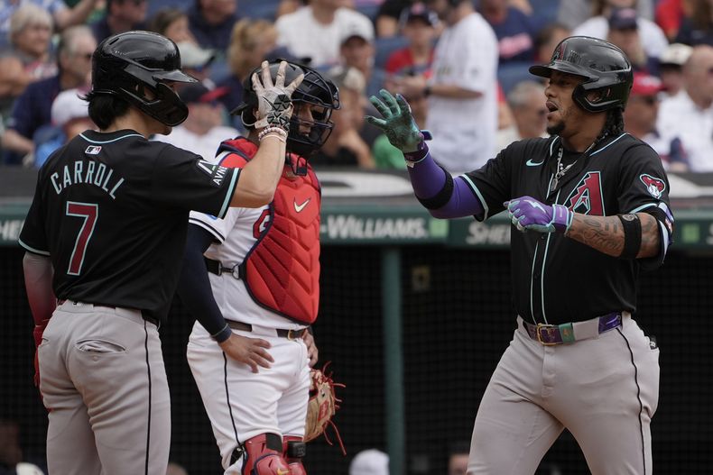 Ketel Marte, de los Diamondbacks de Arizona, a la derecha, celebra su jonrón con su compañero de equipo Corbin Carroll (7) frente al receptor de los Guardianes de Cleveland, Bo Naylor, al centro, en la octava entrada del primer juego de una doble cartelera de béisbol en Cleveland, el miércoles 7 de agosto de 2024. (AP Foto/Sue Ogrocki)