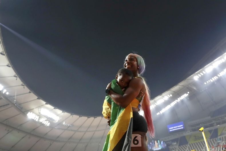 ARCHIVO - Shelly-Ann Fraser-Pryce carga a su hijo Zyon tras ganar la medalla de oro de los 100 metros en el Mundial de atletismo, el 29 de septiembre de 2019, en Doha, Qatar. (AP Foto/Petr David Josek)