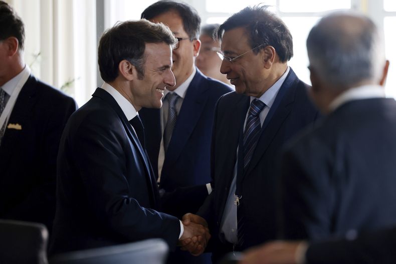 El presidente francés Emmanuel Macron, izquierda, estrecha la mano del director ejecutivo de ArcelorMittal, Lakshmi Mittal, antes de una reunión durante la sexta edición de la cumbre Choose France, en el Palacio de Versalles, en las afueras de París, Francia, el lunes 15 de mayo de 2023. (Ludovic Marin/ Pool Photo via AP)