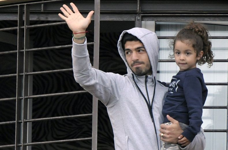 El uruguayo Luis Su&aacute;rez carga a su hija y saluda a los seguidores que acudieron a manifestarle apoyo, desde el balc&oacute;n de su casa en las afueras de Montevideo, el viernes 27 de junio de 2014 (AP Foto/Matilde Campodonico)