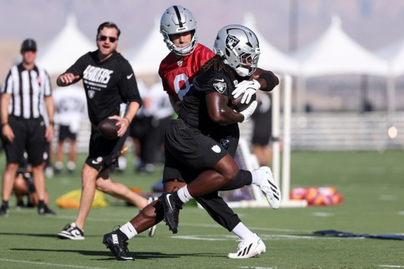 Kirk Cousins (8), quarterback de los Raiders de Las Vegas, entrega el balón al running back Ashton Jeanty (2) durante una práctica del equipo en el campaoento de entrenamiento, el jueves 30 de julio de 2026, en Henderson, Nevada. (AP Foto/Ian Maule)