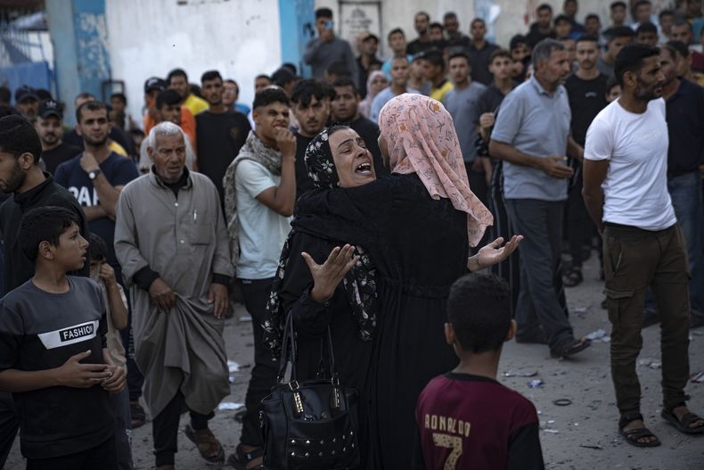 Mujeres llorando mientras se saca a víctimas de entre los escombros de un edificio derruido tras un ataque aéreo en Khan Younis, Franja de Gaza, el sábado 21 de octubre de 2023. (AP Foto/Fatima Shbair)