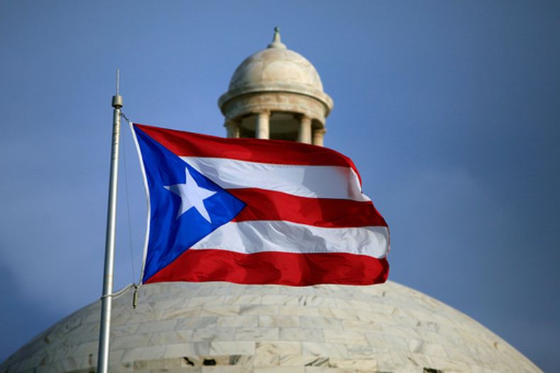 ARCHIVO - Una bandera puertorriqueña ondea frente al edificio del Capitolio en San Juan, Puerto Rico, el 29 de julio de 2015. (Foto AP/Ricardo Arduengo, archivo)