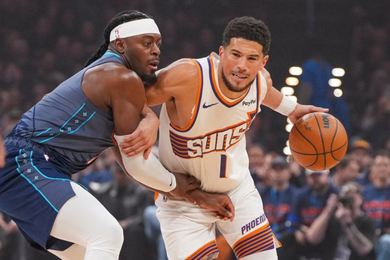 El base de los Suns de Phoenix, Devin Booker, a la derecha, avanza frente al base del Thunder de Oklahoma City, Luguentz Dort, durante la primera mitad del segundo juego de una serie de la primera ronda de los playoffs de la NBA, el miércoles 22 de abril de 2026, en Oklahoma City. (AP Foto/Kyle Phillips)