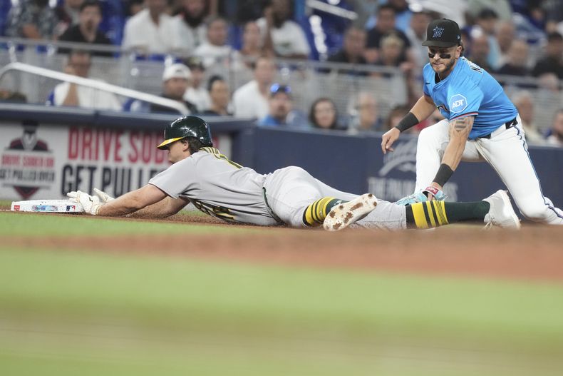 Nick Kurtz, de los Atléticos de Oakland, a la izquierda, golpea el tiro al tercera base de los Marlins de Miami, Connor Norby, a la derecha, para un triple durante la novena entrada de un juego de béisbol, el domingo 4 de mayo de 2025, en Miami. (AP Foto/Lynne Sladky)