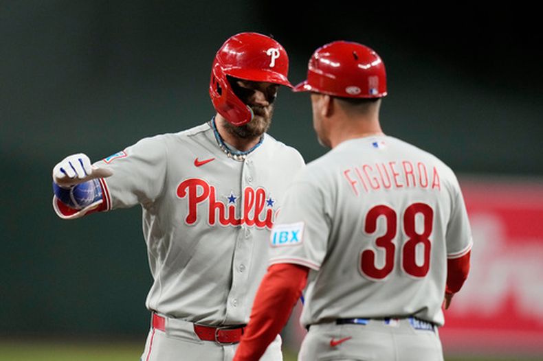 Bryce Harper, de los Filis de Filadelfia, festeja con el coach de la inicial Paco Figueroa, luego de pegar un sencillo en el juego ante los Diamondbacks de Arizona, el martes 1 de septiembre de 2026 (AP Foto/Ross D. Franklin)