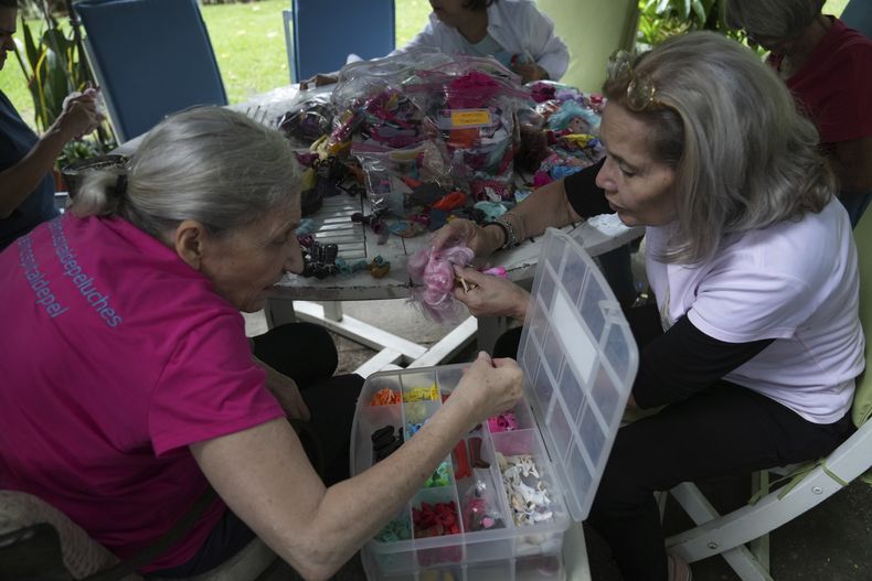 Una voluntaria busca entre una selección de zapatos de muñecas en miniatura en la organización sin fines de lucro Hospital de los Peluches, en donde recuperan y reparan juguetes usados para donarlos a niños vulnerables como regalos de Navidad, en Caracas, Venezuela, el jueves 5 de diciembre de 2024. (AP Foto/Ariana Cubillos)