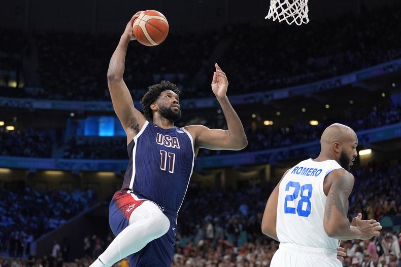 El estadounidense Joel Embiid clava el balón ante el puertorriqueño Ismael Romero en el baloncesto de los Juegos Olímpicos de París, el sábado 3 de agosto de 2024, en Villeneuve-dAscq, Francia. (AP Foto/Michael Conroy)