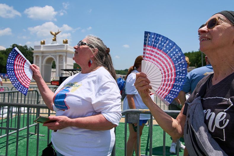 ARCHIVO - Mickelina Papotto, de Salem, Oregon, izquierda, y Lorie Odegaard, de Gaithersburg, Maryland, se abanican mientras esperan en una fila para subir a la rueda de la fortuna en la Gran Feria Estatal de Estados Unidos, en el National Mall, el 1 de julio de 2026, en Washington. (AP Foto/Jacquelyn Martin)